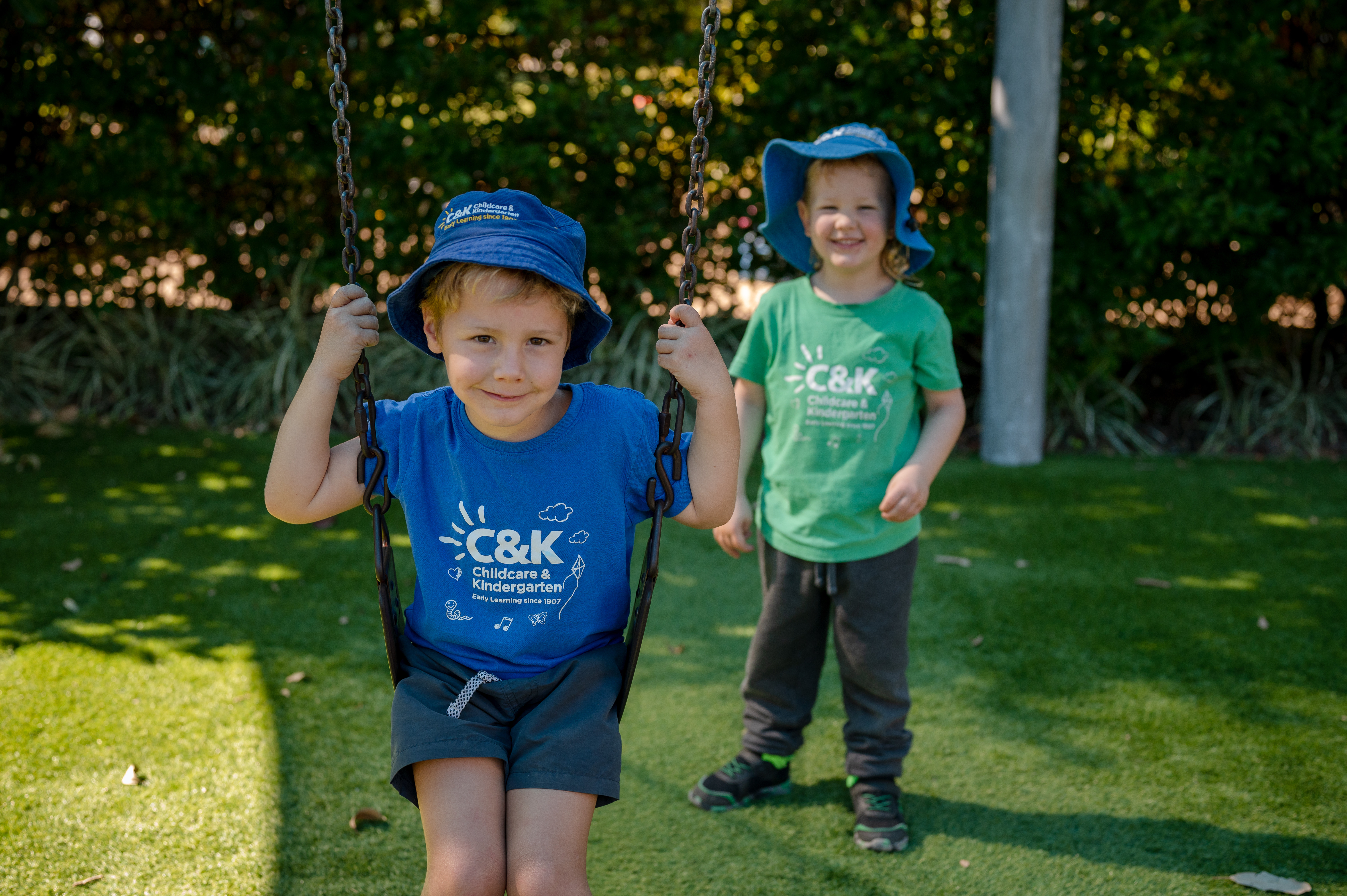 Child on swing being pushed by friend