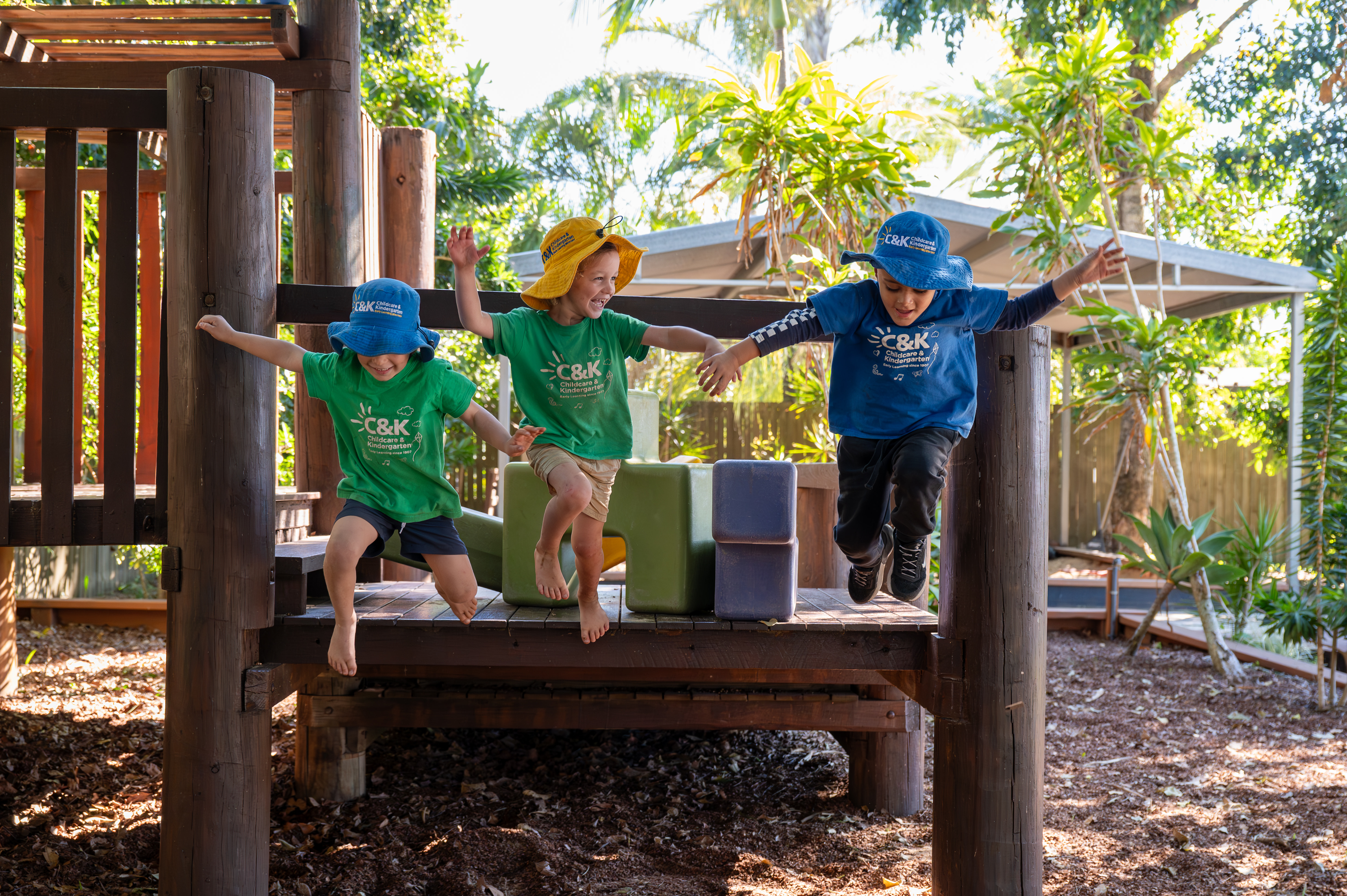 Three children jumping off a playground