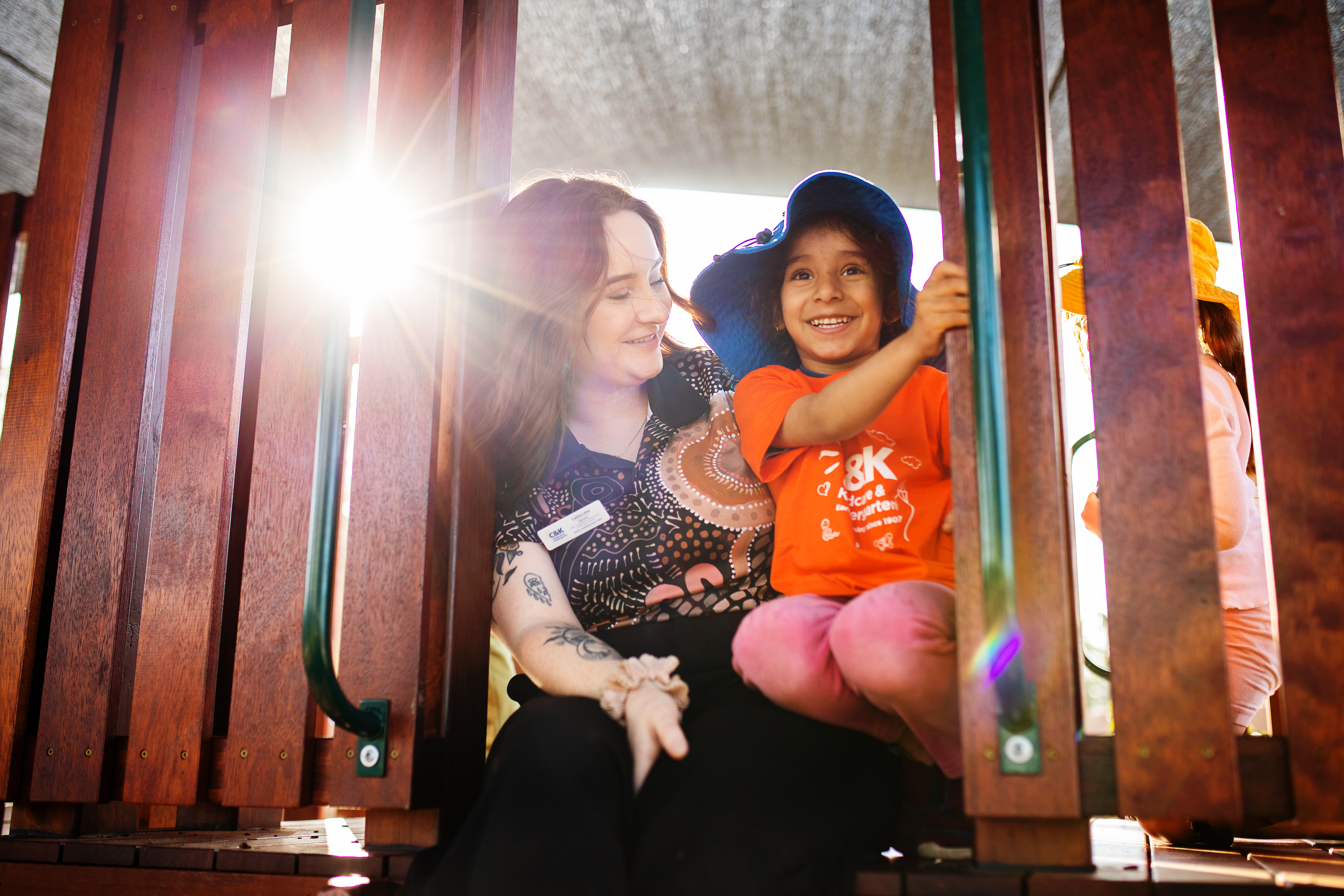 Female educator on playground with one child.