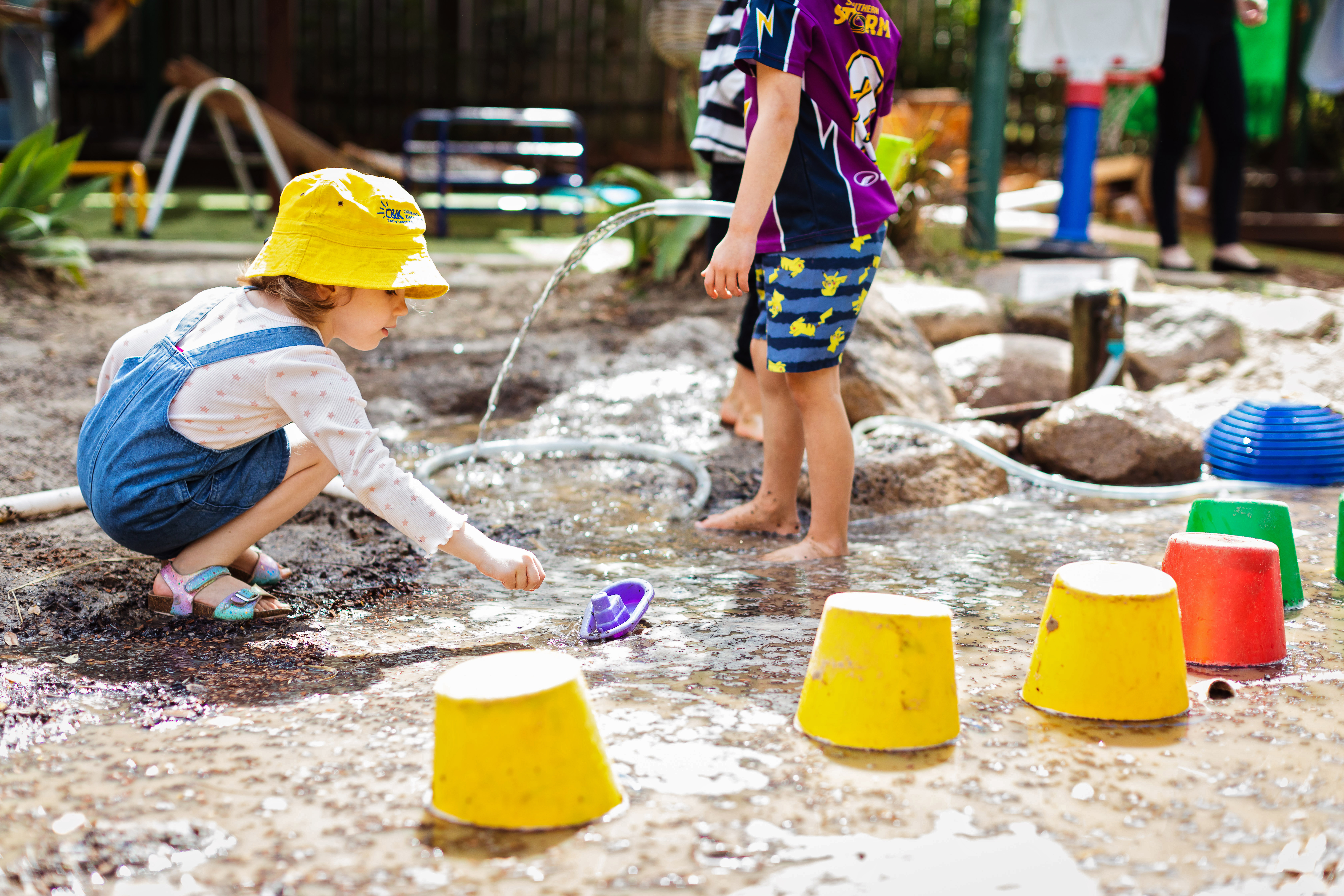 Two children outside playing with water and utensils 