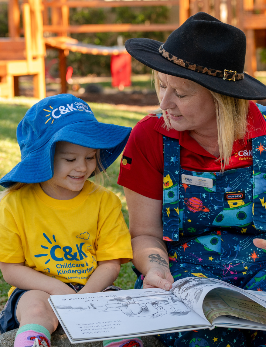 C&K teacher and child reading outside