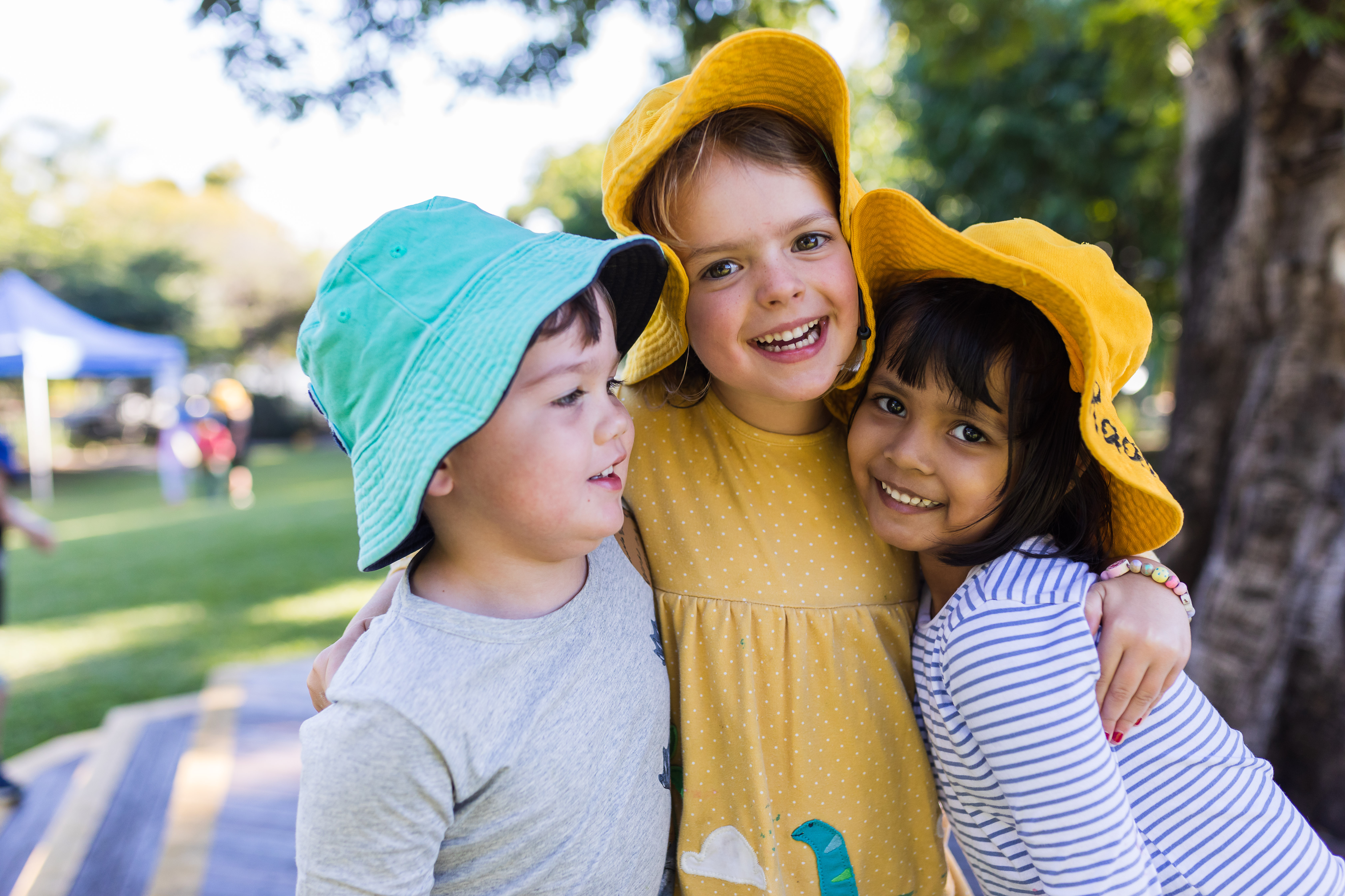 Three kindy children hugging and smiling