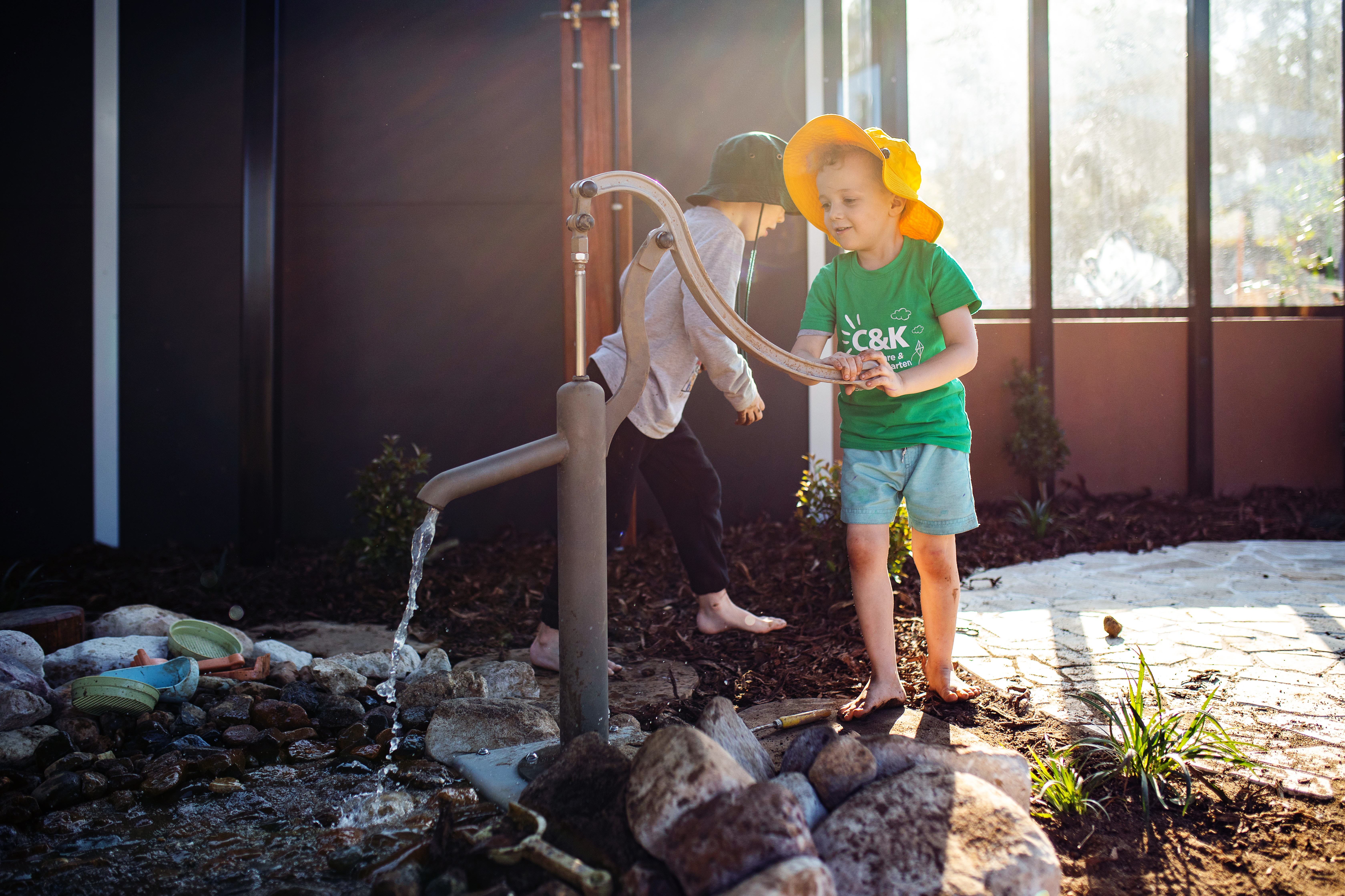 Two children playing with tap outside