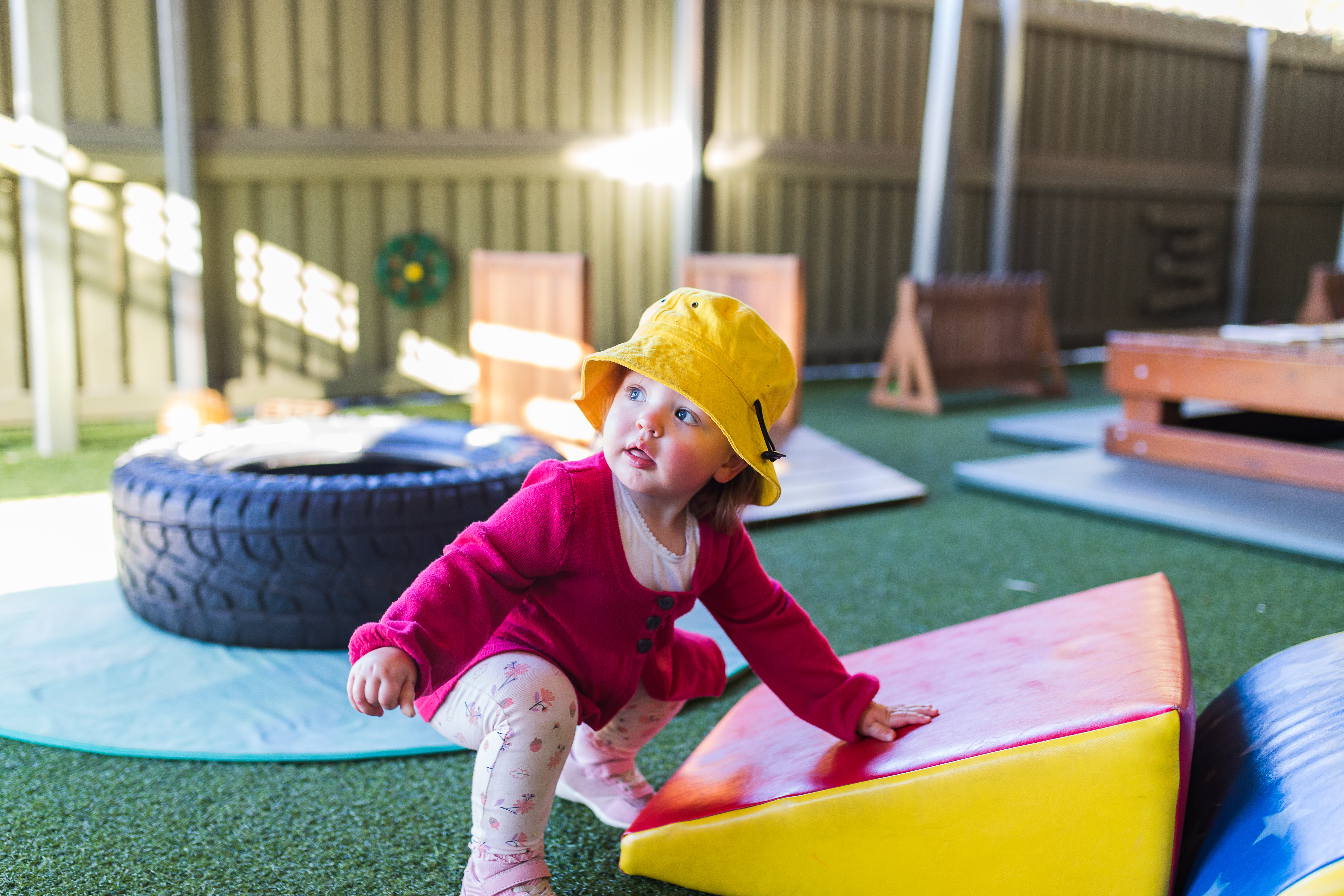 Toddler playing outside with soft obstacles for climbing